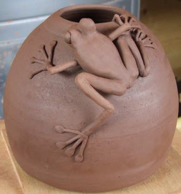 a clay pot with a frog sitting on it