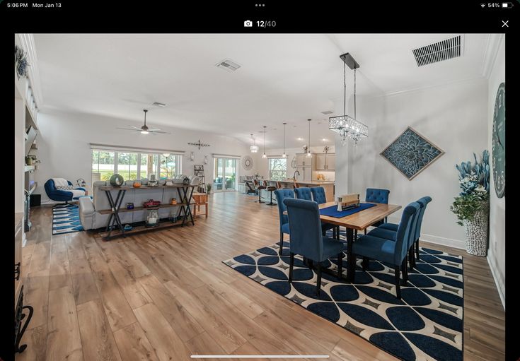 a large open floor plan living room and dining room with hardwood floors, white walls, and blue chairs