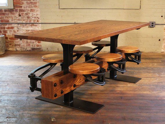 a wooden table with four stools underneath it in an industrial style room, next to a brick wall