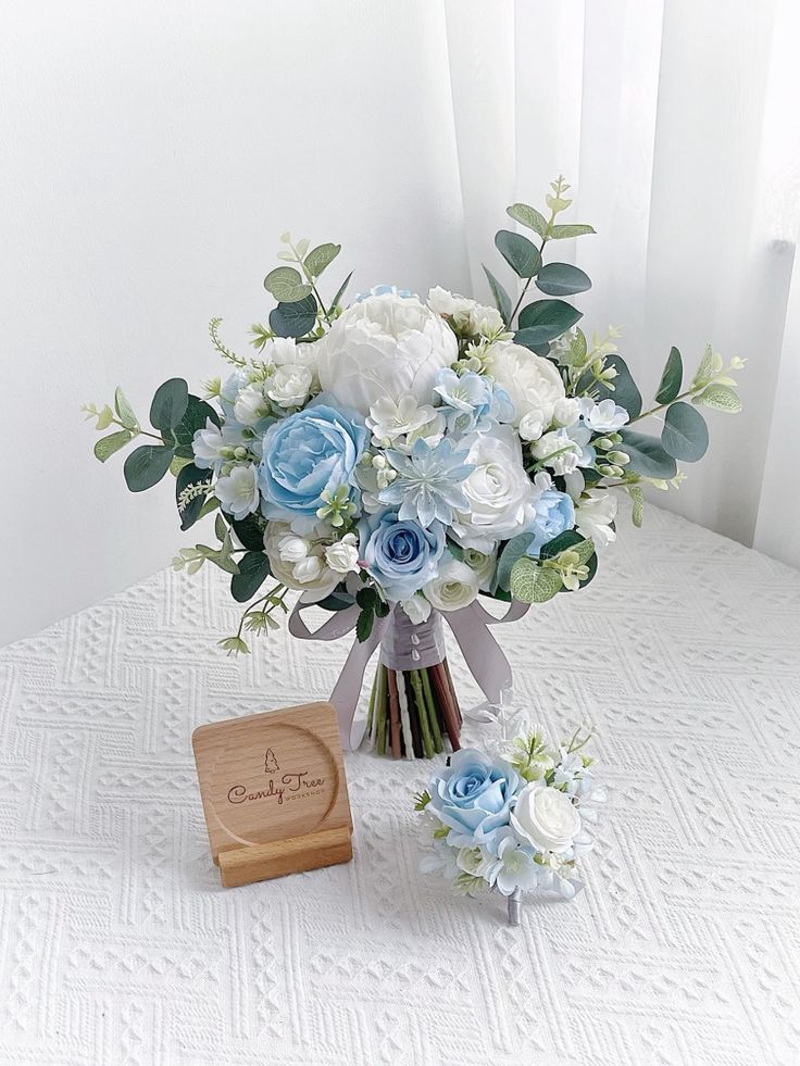 a bouquet of blue and white flowers sitting on a table next to a wooden box