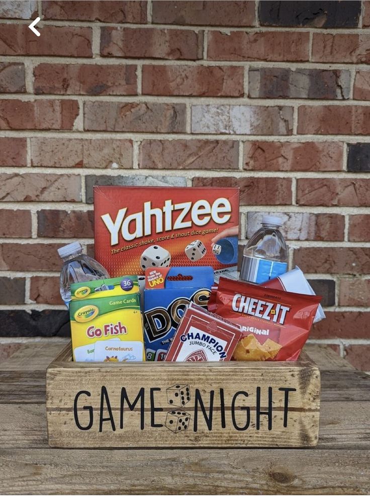 a game night gift box filled with candy and snacks sitting on a wooden crate in front of a brick wall