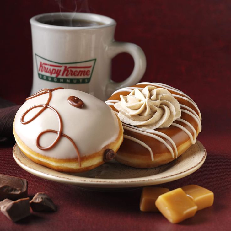 two donuts on a plate next to a cup of coffee and pieces of chocolate