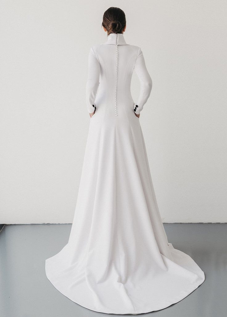 the back of a woman in a white wedding dress, with her hands on her hips