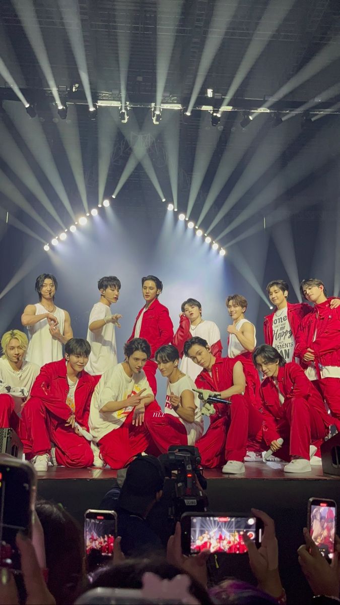 a group of young men standing on top of a stage with their cell phones in front of them