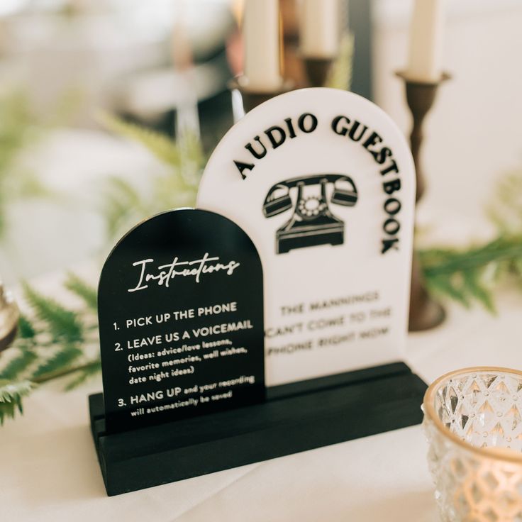 a black and white sign sitting on top of a table next to a candle holder