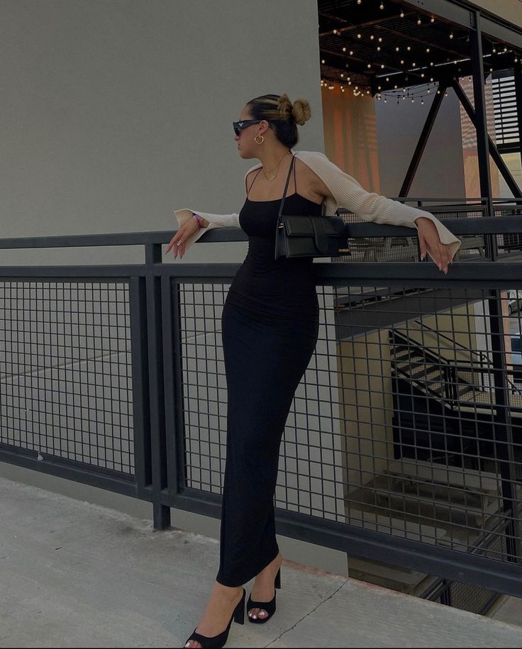 A girl is leaning against a railing with a long black, skin tight dress on. She’s  wearing black heels, a beige shrug, and a little black purse. Body Con Maxi Dress Outfit, Brunch Date Outfit Summer, Long Bodycon Dress Outfit, Black Bodycon Dress Outfit, Long Black Dress Outfit, Long Black Bodycon Dress, Tight Maxi Dress, Bodycon Dress Outfit, Black Midi Dress Bodycon