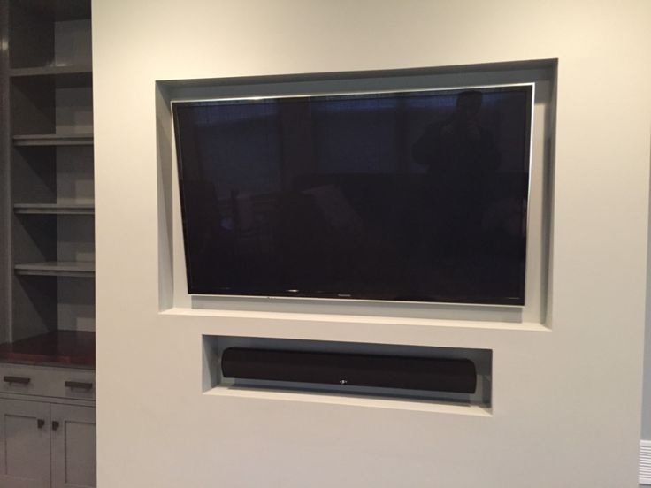 a flat screen tv mounted to the side of a wall in a room with white cabinets