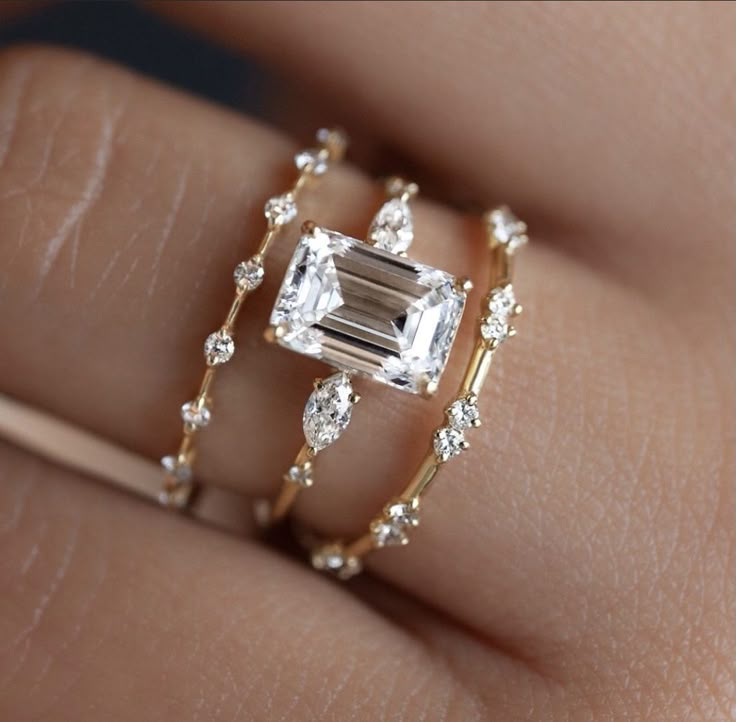 a close up of a person's hand wearing a ring with an emerald stone