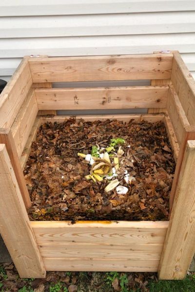 a wooden planter filled with dirt and leaves