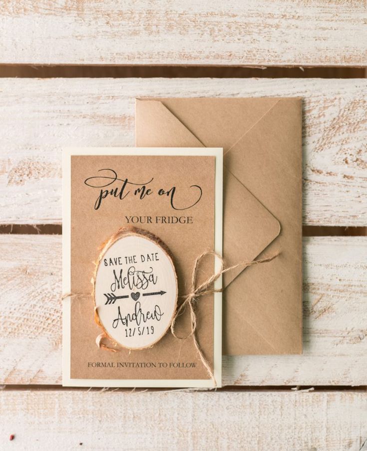 an envelope and save the date magnets on top of a wooden table with twine