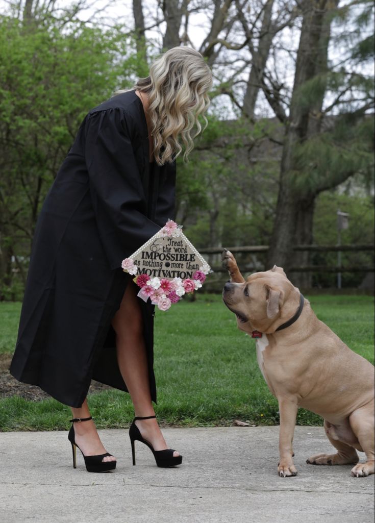 a woman kneeling down next to a dog and touching her nose with the other hand