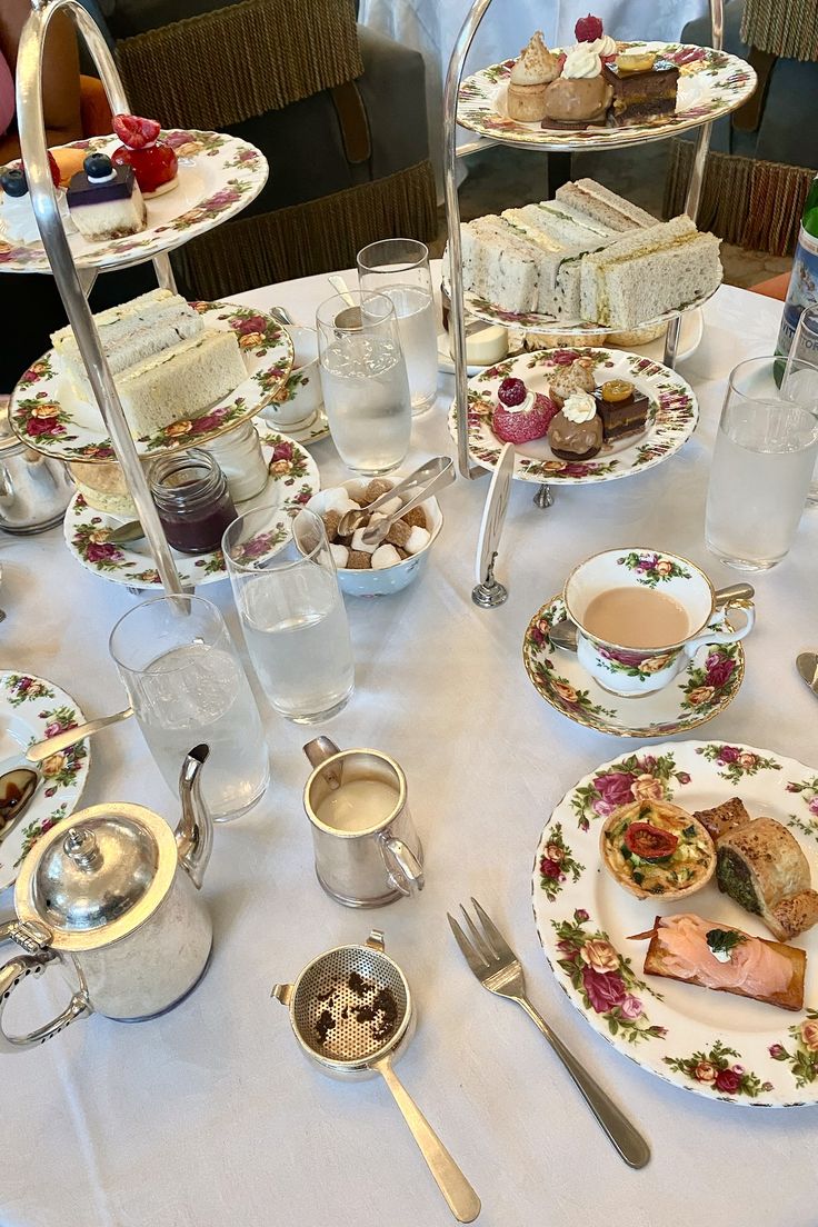 a table topped with plates and cups filled with food next to silver ware on top of a white table cloth