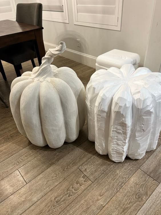 two white pumpkins sitting on the floor next to each other