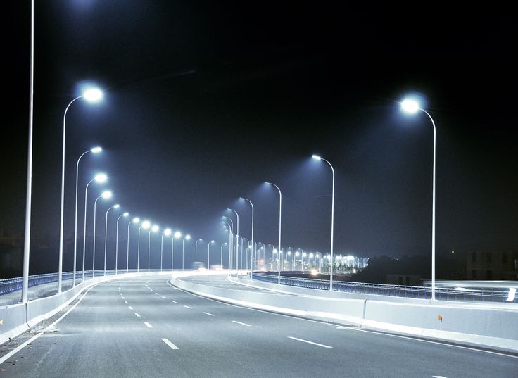 an empty street at night with lights on the sides and no cars driving down it