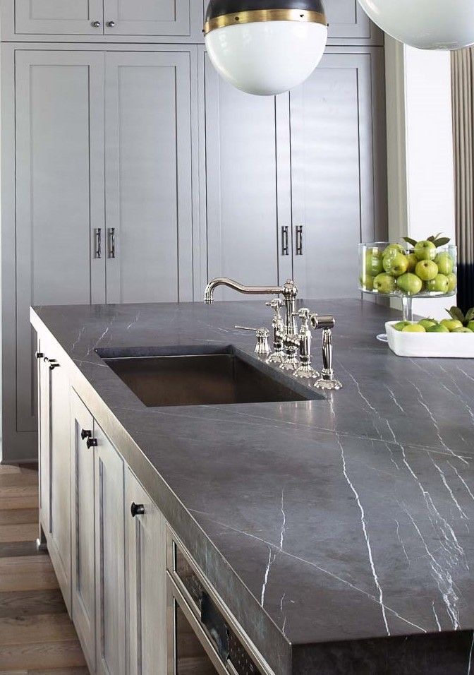 a kitchen with marble counter tops and white cupboards in the backround area