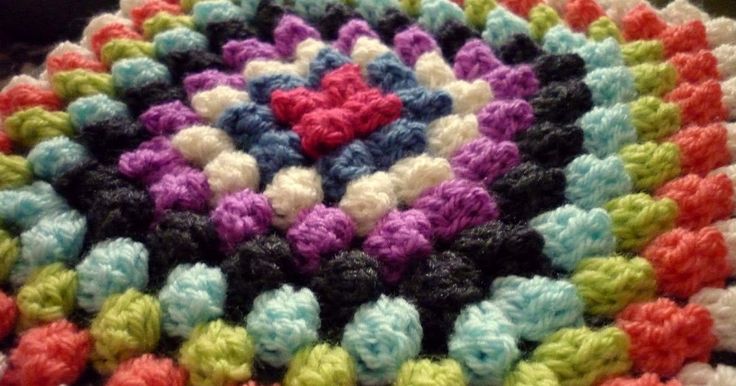 a multicolored crocheted rug with hearts on it sitting on a table