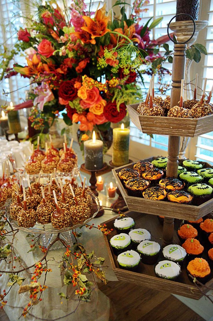 an assortment of desserts and cupcakes on a table with flowers in the background