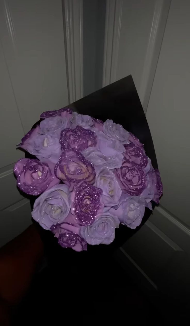 a bouquet of purple flowers sitting on top of a black table next to a door