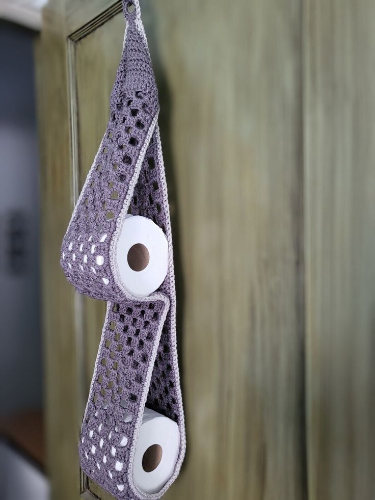 two rolls of toilet paper are hanging from a cabinet