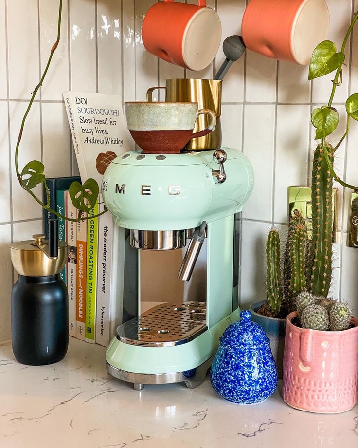 Mint green retro style Smeg coffee machine styled in electric kitchen with ceramic mugs, cook books and cacti plants. Mint Green Kitchen Decor, Smeg Mint Green, Smeg Appliances In Kitchen, Smeg Green, Coffee Machine Station, Smeg Aesthetic, Smeg Espresso Machine, Green Smeg, Smeg Coffee Machine