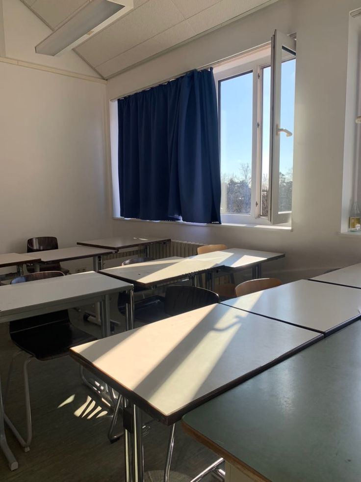 an empty classroom with desks and windows