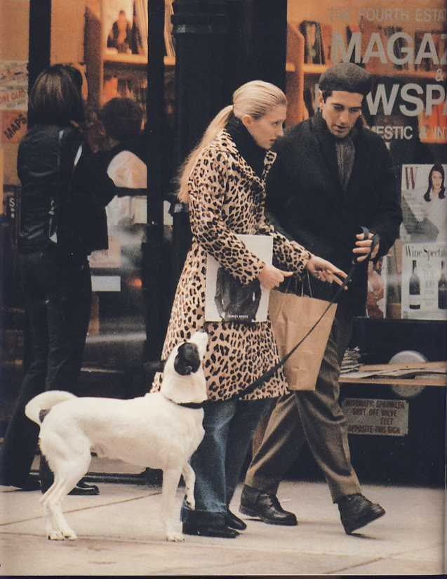 a man and woman walking their dog down the street