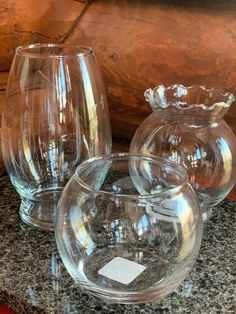 three clear glass vases sitting on top of a granite counter next to each other