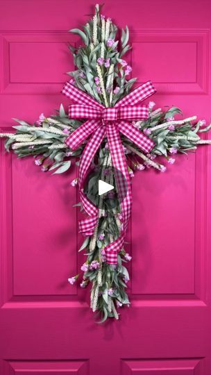 a pink door with a cross hanging from it's side and flowers on the front