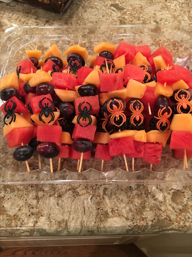 a tray filled with watermelon, oranges and blackberries covered in halloween decorations