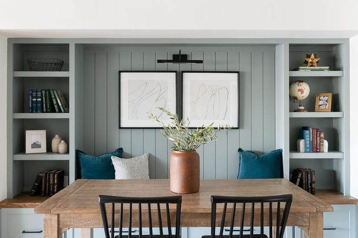 a dining room table and chairs with bookshelves in the background