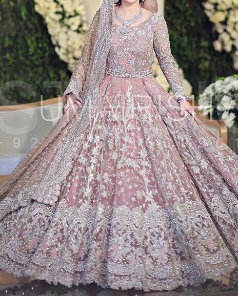 a woman in a wedding gown with long sleeves and an elaborate skirt on the runway