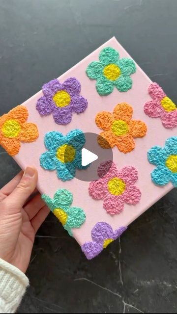 someone is holding up a pink and yellow flowered paper art work on a black surface