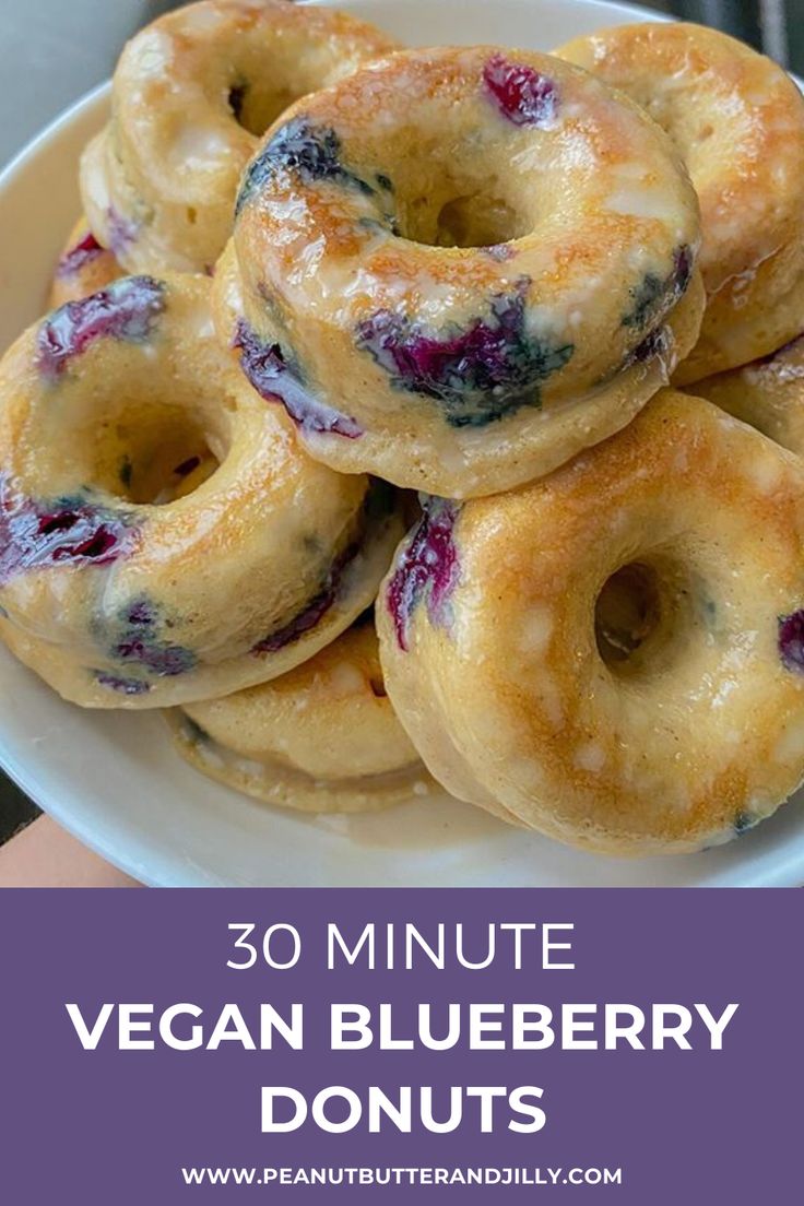 blueberry donuts stacked on top of each other in a white bowl with text overlay that reads 30 minute vegan blueberry donuts