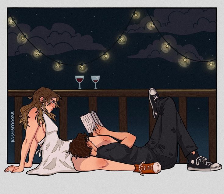 a man and woman laying on the ground reading books at night with lights in the background