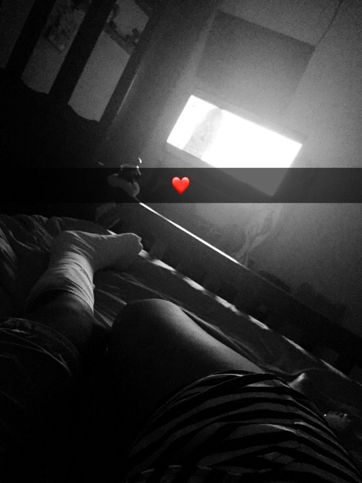 a person laying in bed under a window with a red heart on it