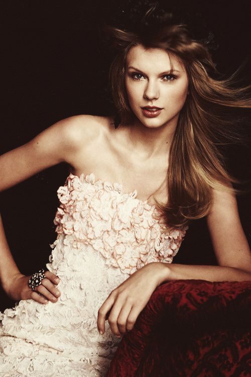 a woman in a strapless dress is posing for a magazine spread with her hair blowing in the wind