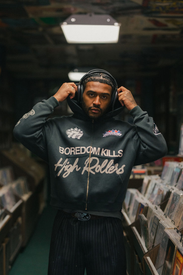 a man with headphones on his ears standing in a room full of cd's