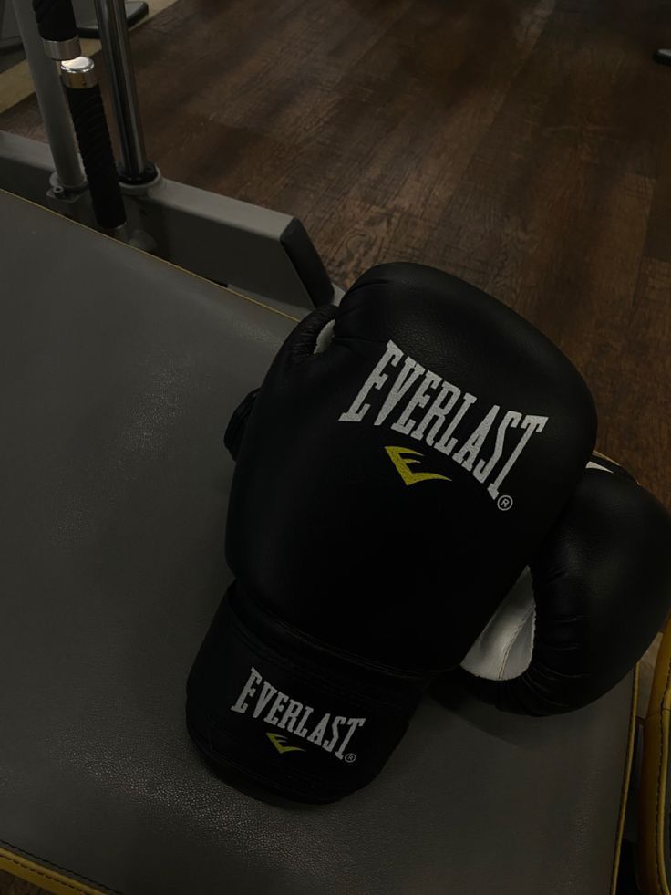 a pair of black boxing gloves sitting on top of a gym equipment rack in a gym