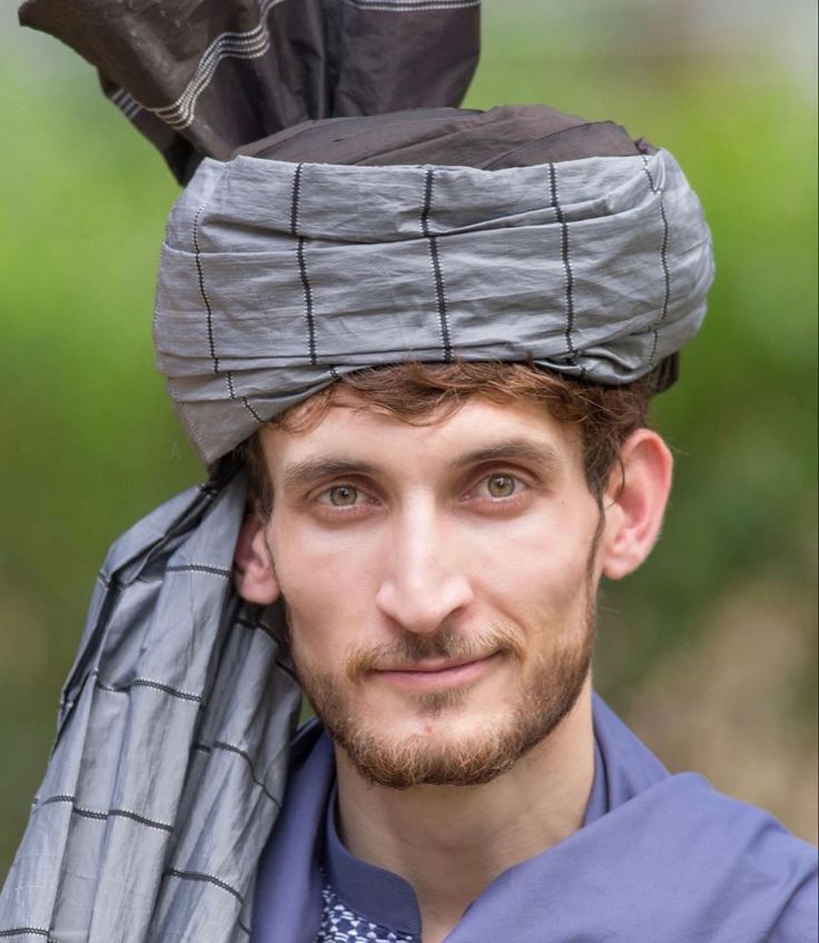 a man wearing a hat with feathers on it's head and a scarf around his neck