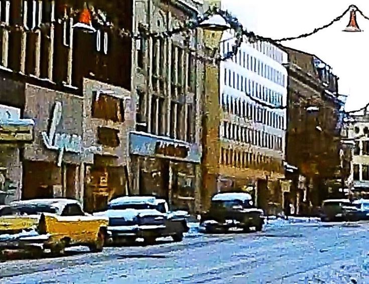 the cars are parked on the side of the road in the snow covered city street