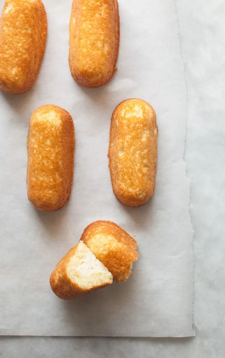 four doughnuts with one bite taken out and the other half eaten on a piece of parchment paper