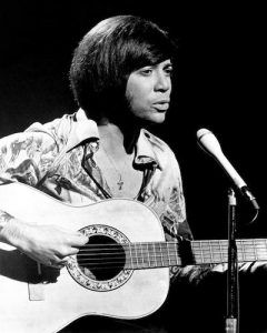 a man holding a guitar in front of a microphone