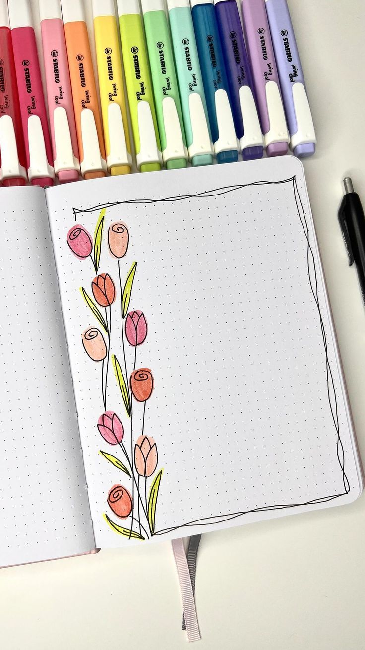 an open notebook with markers and flowers on it