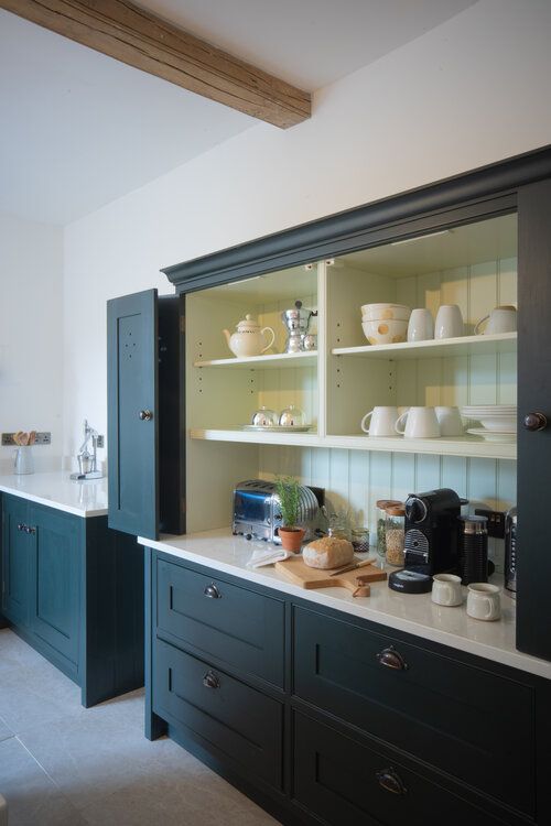 a kitchen with green cupboards and white counter tops in front of the sink area