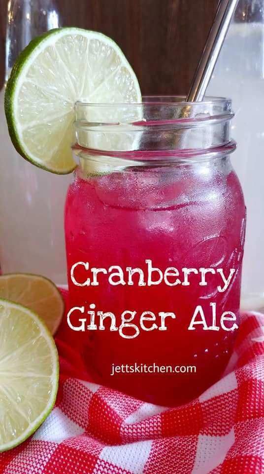 a close up of a mason jar with a drink in it and two limes on the side