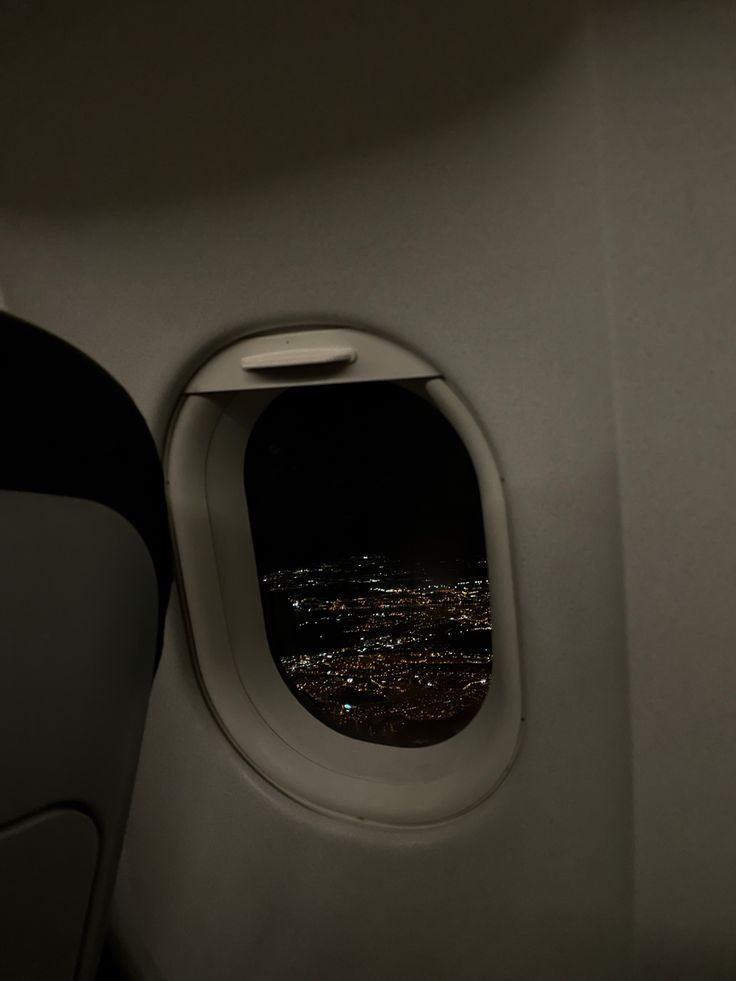 an airplane window looking out at the city lights