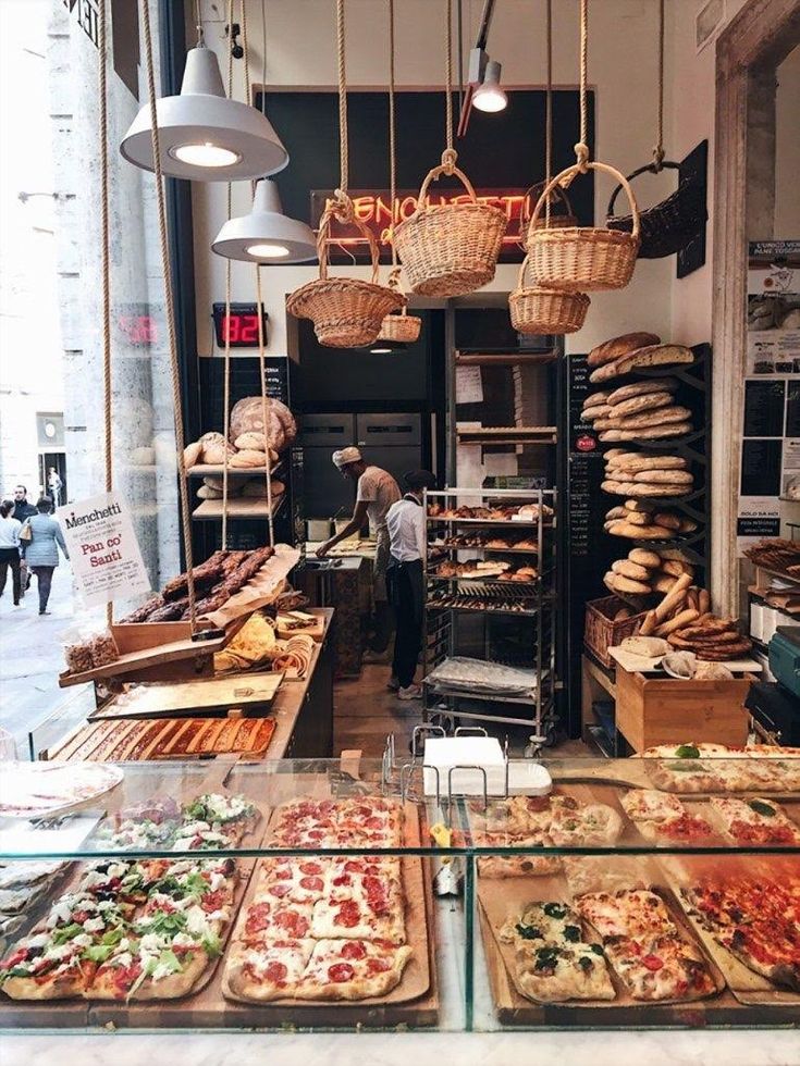 a bakery filled with lots of different types of pizzas and other food on trays