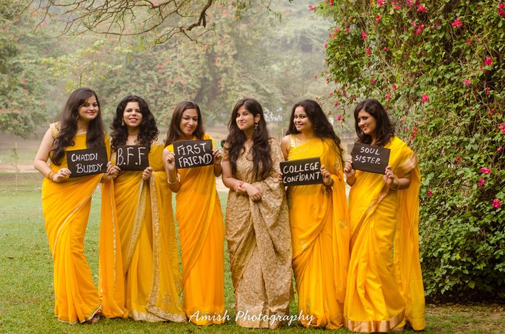 a group of women standing next to each other in yellow saris holding up signs