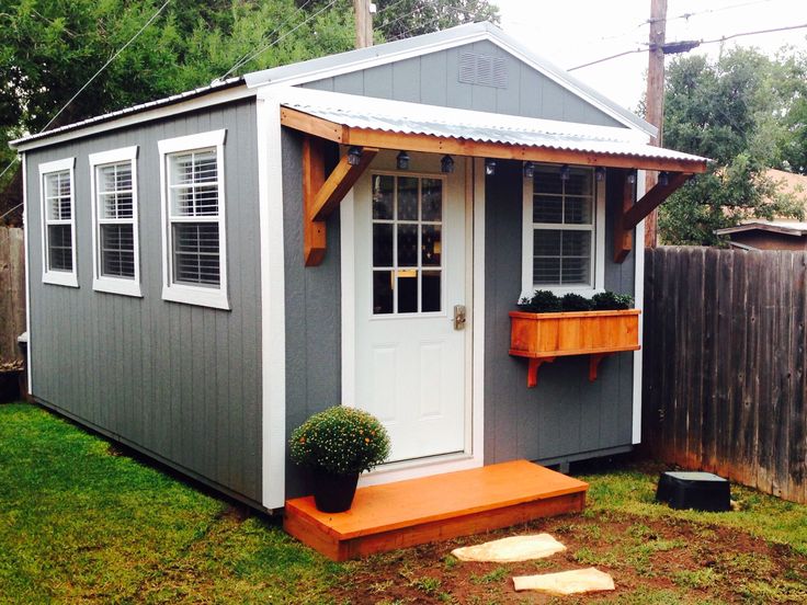 a small gray and white shed with an orange step leading up to the front door