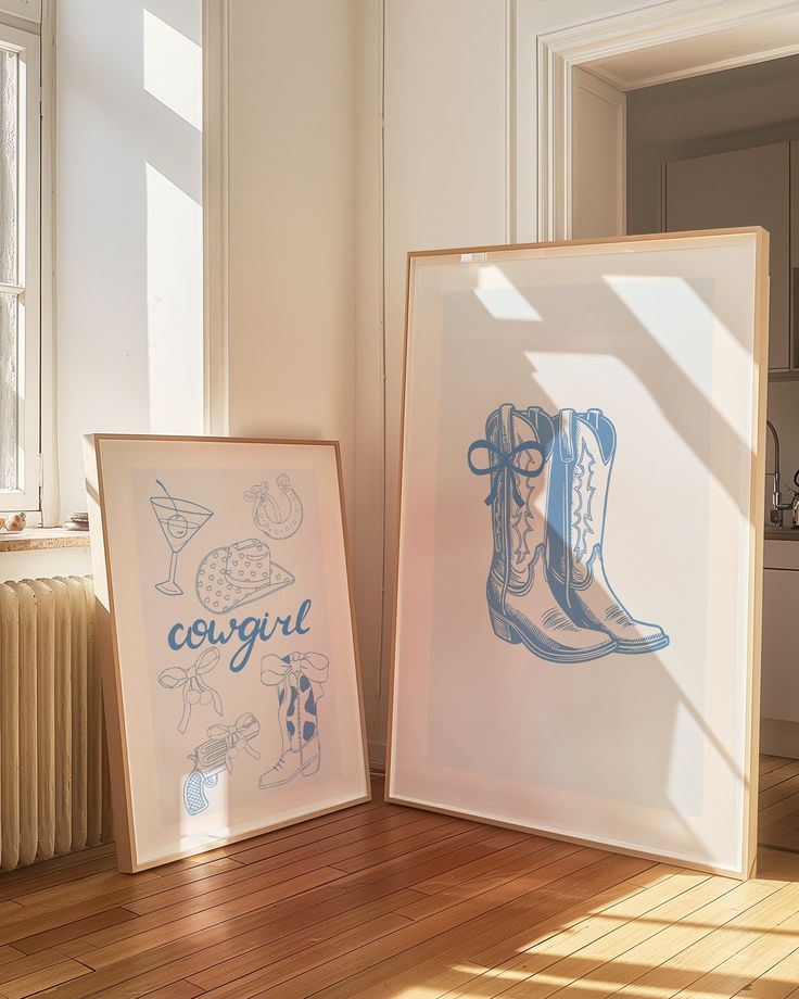 two framed pictures sitting on top of a wooden floor